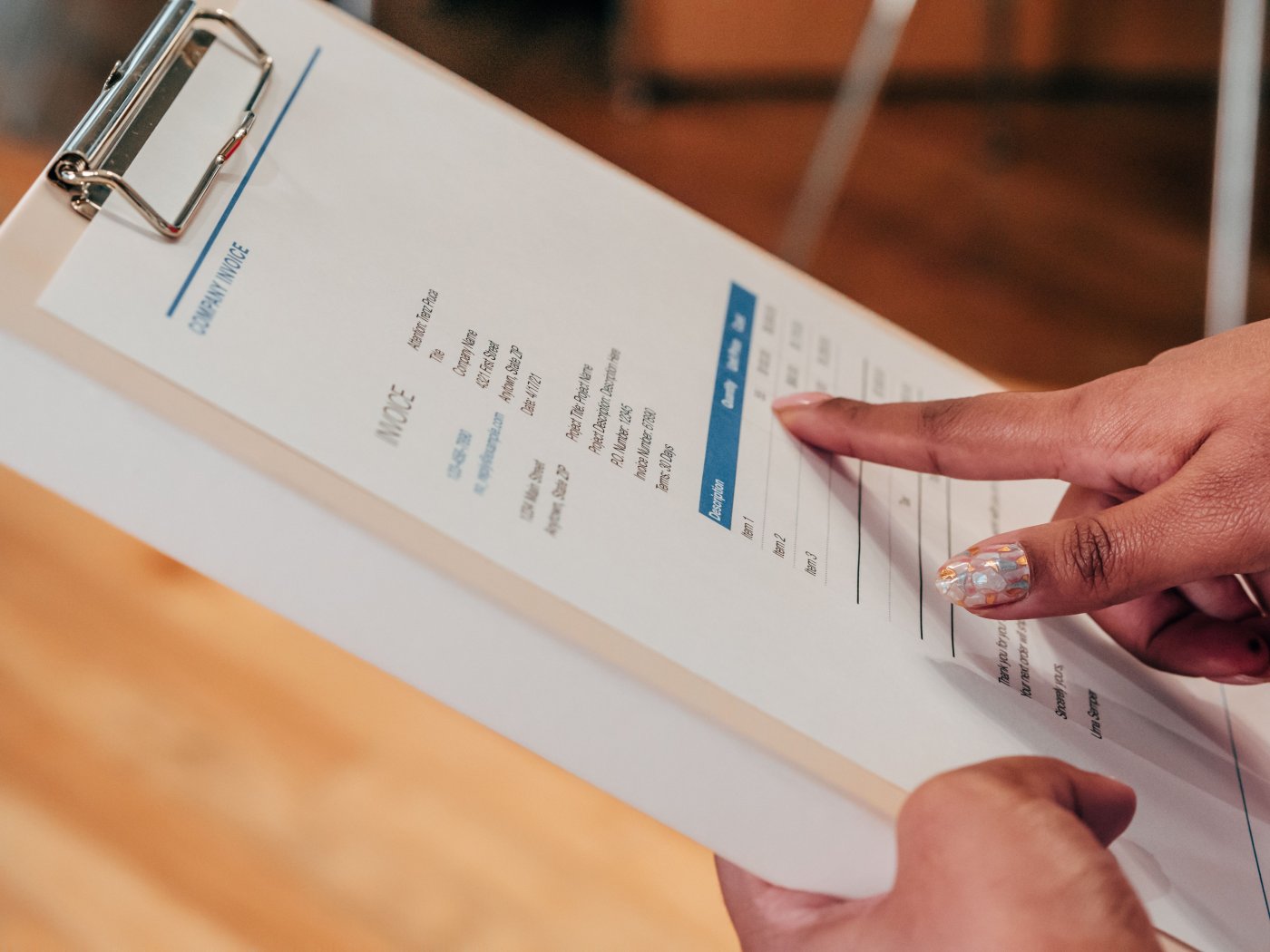 A person pointing at an invoice on a clipboard