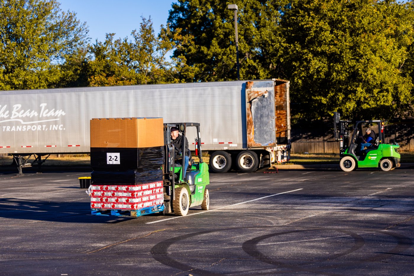Forklift operators loading pallets onto a delivery truck